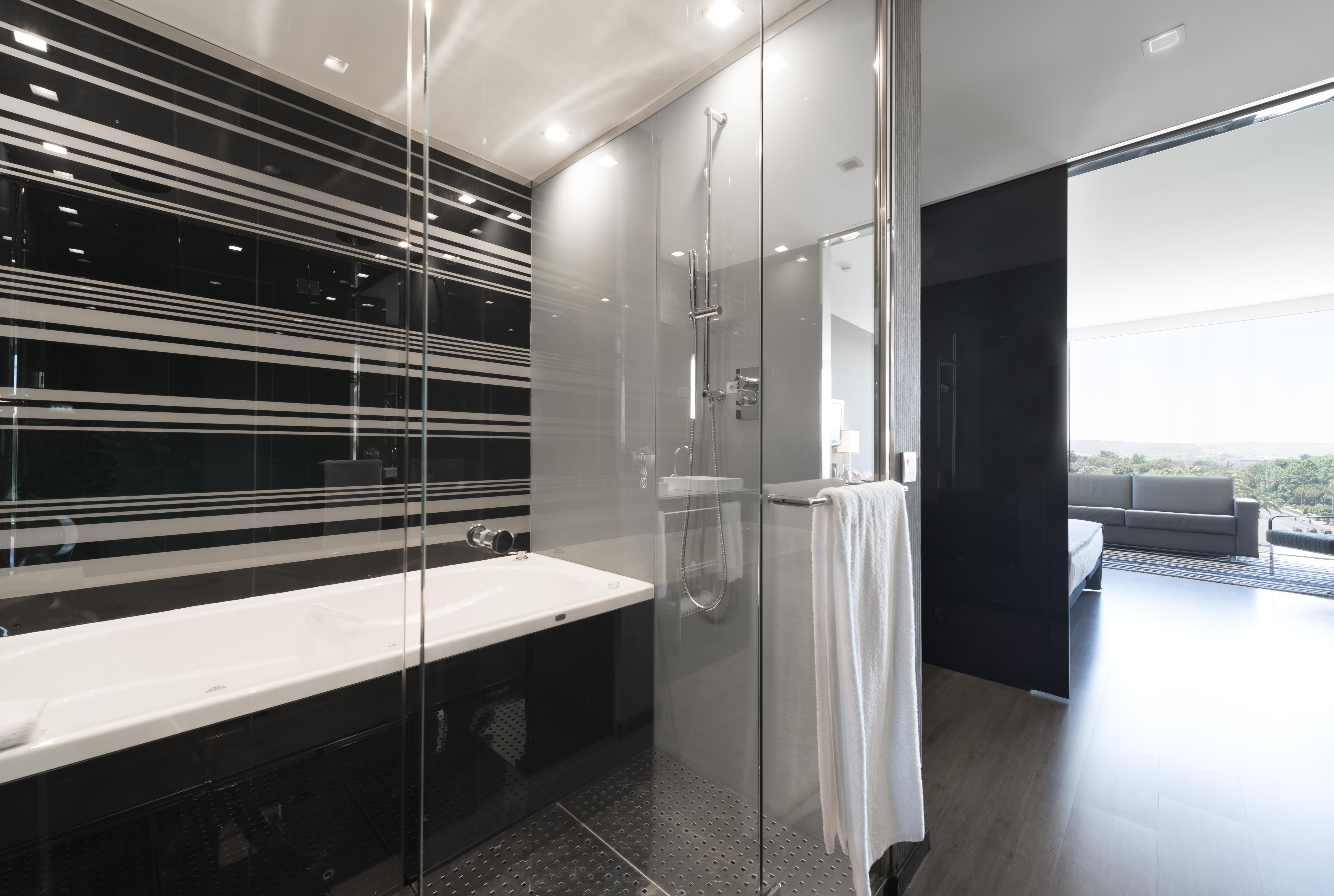 Eurostars Palace Cordoba Ngoại thất bức ảnh The photo shows a modern bathroom featuring a sleek design. On one side, there is a glass-enclosed shower with contemporary fixtures. Adjacent to it, there's a stylish bathtub with a clean, white surface. The walls are decorated with a striking patte