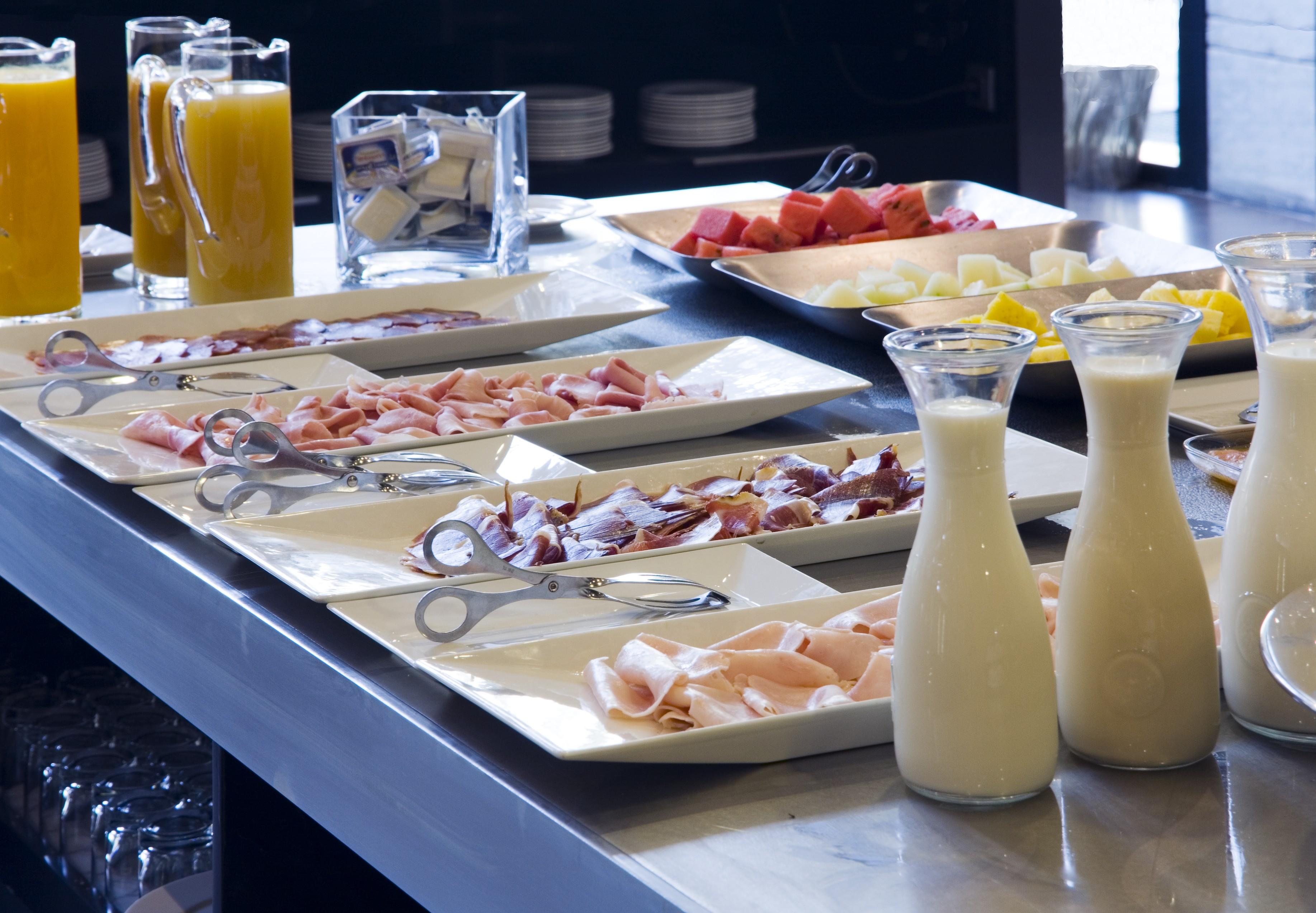 Eurostars Palace Cordoba Ngoại thất bức ảnh The photo displays a buffet area with various food items arranged on a countertop. There are multiple plates featuring an assortment of sliced meats, likely including ham and possibly turkey or chicken. Additionally, two glass pitchers are filled wit