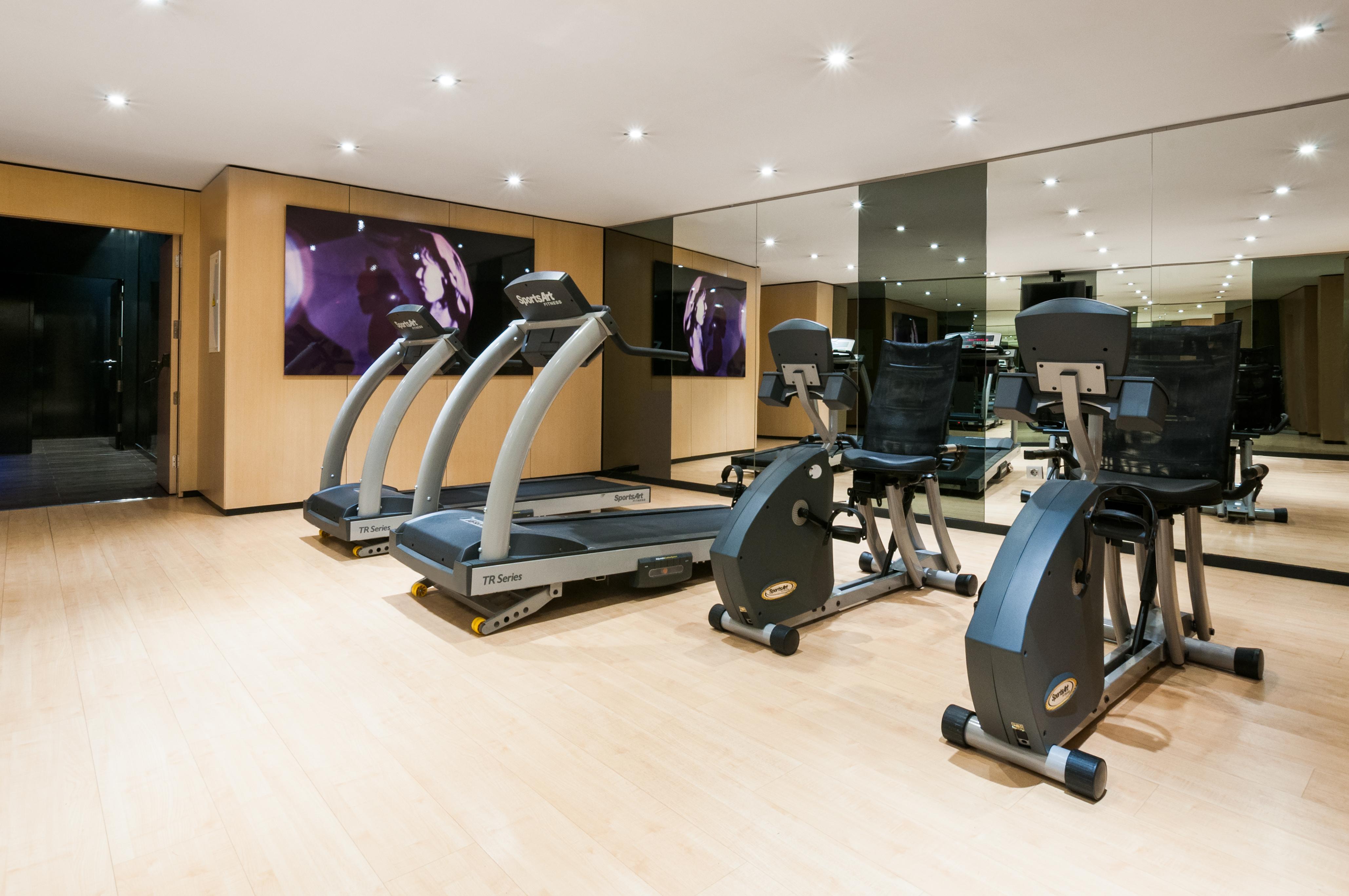 Eurostars Palace Cordoba Ngoại thất bức ảnh The photo shows a modern gym or fitness area. It features several pieces of exercise equipment, including treadmills and stationary bikes. The room has bright lighting and a wooden floor, contributing to a clean and open atmosphere. There is a large 
