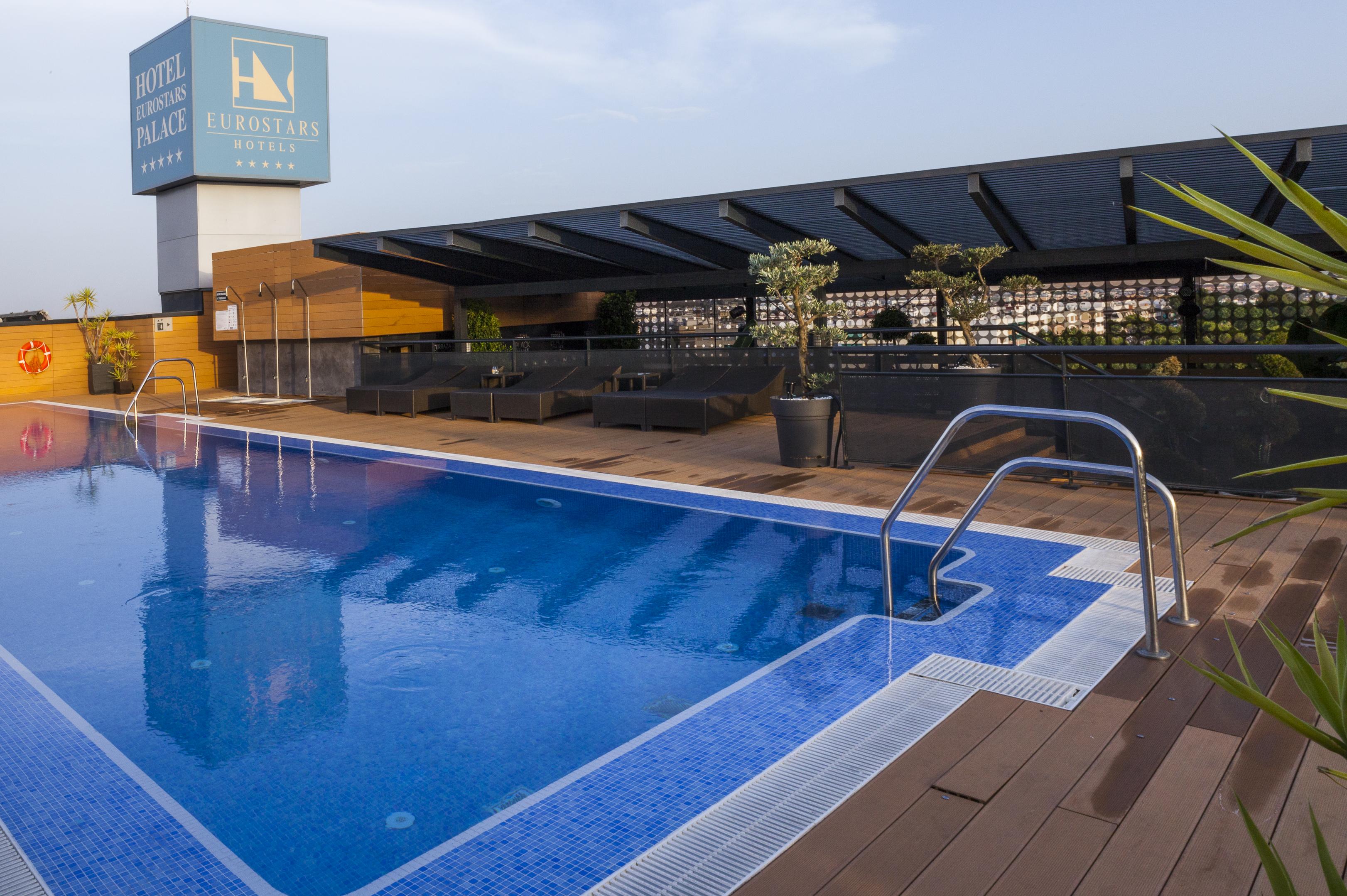 Eurostars Palace Cordoba Ngoại thất bức ảnh The photo shows a rooftop swimming pool with a clear blue water surface. There is a section of the pool with a ladder for entry, and the surrounding area includes wooden decking. In the background, there is a sign for a hotel, which appears to be nam