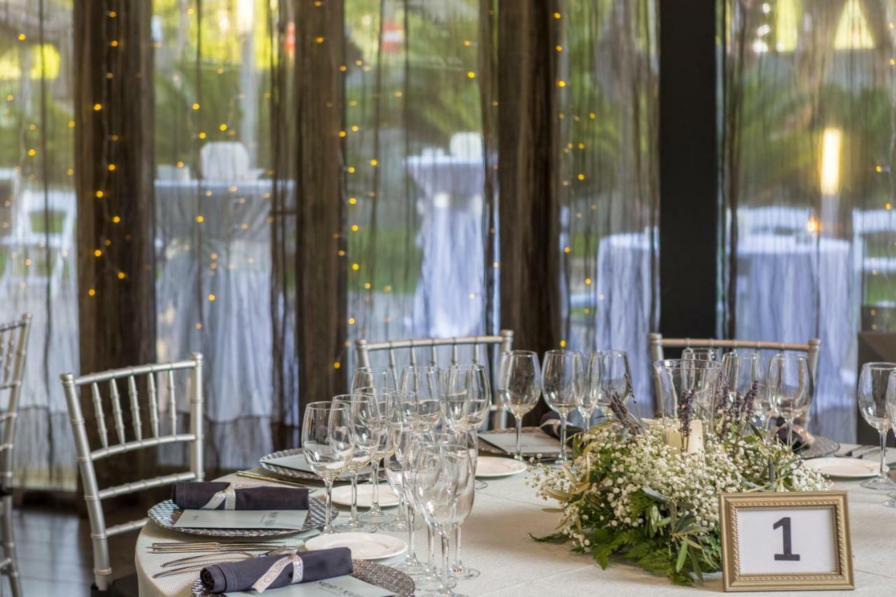 Eurostars Palace Cordoba Ngoại thất bức ảnh The photo shows a beautifully set dining table in an elegant event space. The table is round, covered with a white tablecloth, and adorned with a centerpiece of greenery and flowers. There are several wine glasses and water glasses arranged neatly on