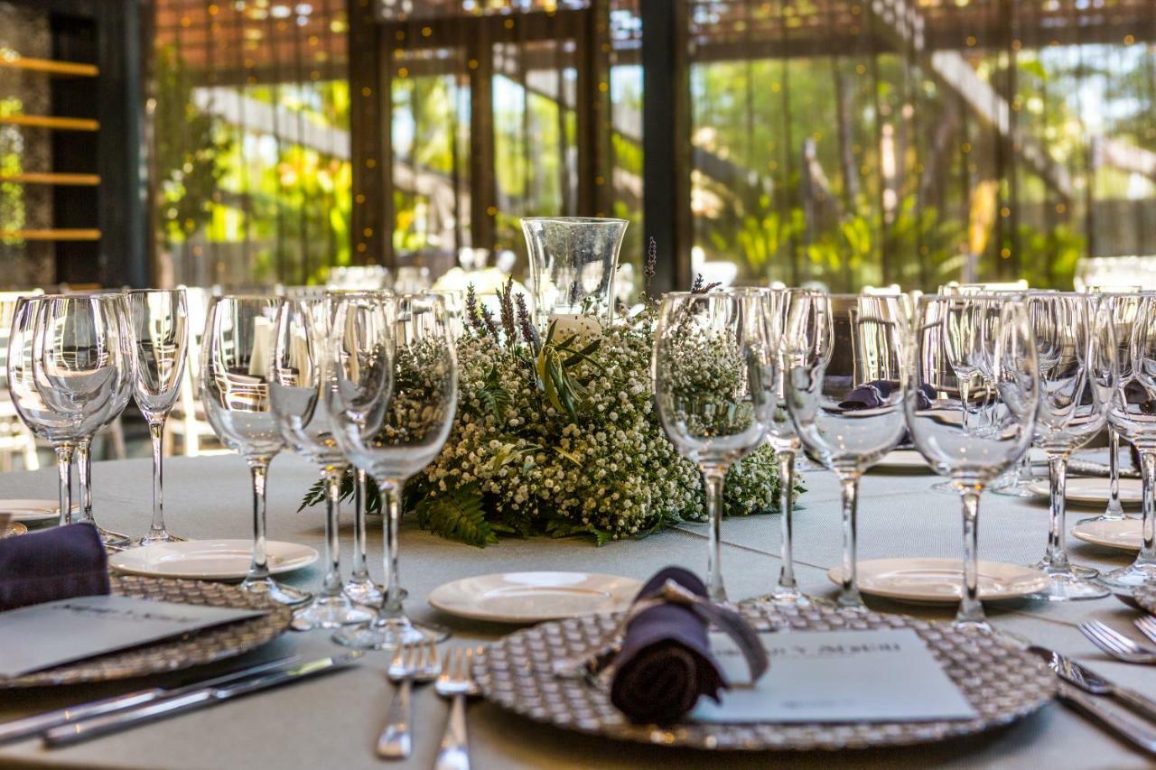 Eurostars Palace Cordoba Ngoại thất bức ảnh The photo displays an elegantly set dining table arranged for a formal event. The table is adorned with a centerpiece made of white flowers and greenery, surrounded by numerous glassware, including wine glasses and water goblets. Each place setting i